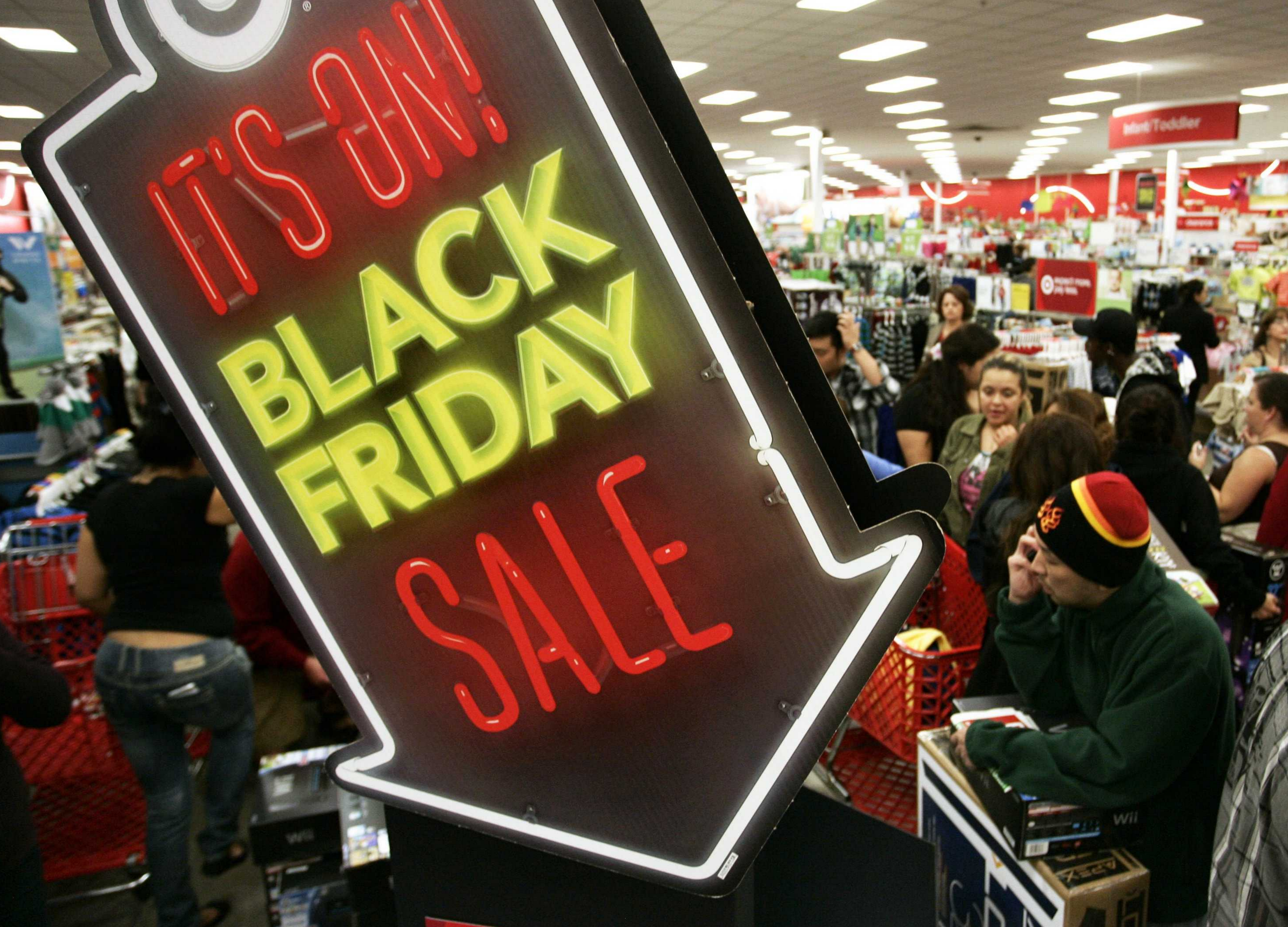 Image of a Black Friday neon arrow sign with crowds of shoppers behind it.